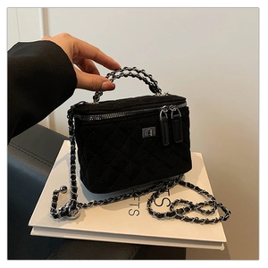 Detail of black quilted suede box bag with silver hardware and chain top handle