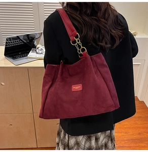 Close-up of burgundy tote bag showing matte texture and gold chain shoulder strap details