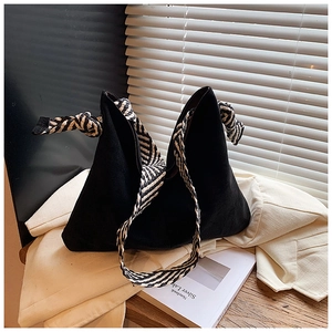 Detail of matte black bucket bag featuring stylish black and white striped woven strap