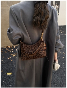 Détail d'un sac à bandoulière léopard avec fermoir doré et pendentifs en perles de bois
