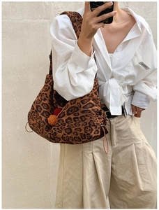 Detail of leopard print tote bag with plush pom-poms and adjustable side drawstrings