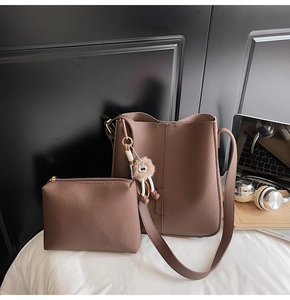 Gros plan du sac seau marron en cuir grainé avec pochette assortie et breloque peluche