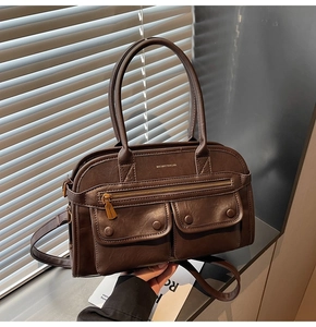 Detailed shot of dark brown retro leather handbag with dual front pockets and top handles
