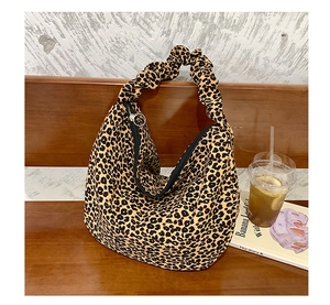 Detail of leopard print hobo bag featuring a pleated handle and metal ring zipper on a chair