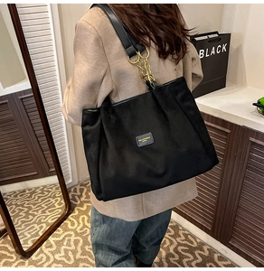 Detail of a black large-capacity tote bag with golden chain and sleek leather straps