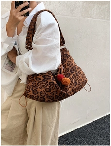 Detail view of large leopard print tote bag with plush colorful charms on a shoulder strap