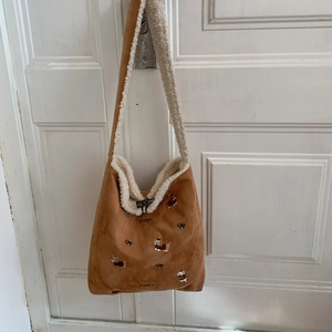 Detail of corduroy shoulder bag showing puppy embroidery and faux fur trim finish