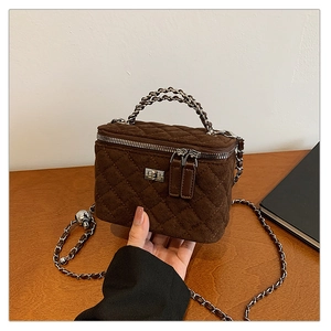Detail of dark brown quilted suede box bag showing metal turn-lock and chain strap