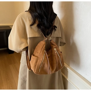 Detailed view of brown frosted leather tote with metallic zippers and long tassels