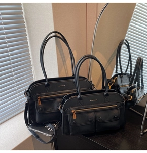 Detail view of black multi-pocket tote and handbag with golden hardware and brand logo