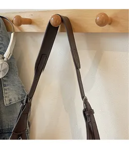 Detail eines verstellbaren dunkelbraunen Leder-Schultergurts mit Metall-Schnalle