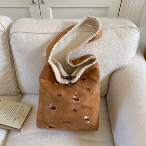 Detail of corduroy bucket bag featuring puppy embroidery and a retro horn toggle button