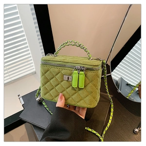 Detail of green quilted suede bag featuring silver chain strap and metal top handle