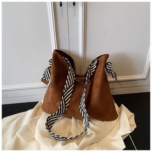Detail of coffee brown suede tote bag featuring a black and white striped woven strap
