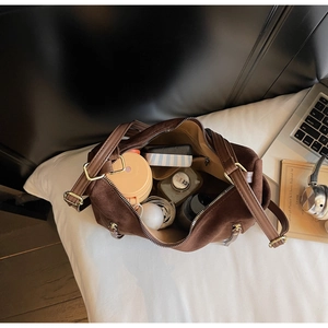 Top view of large capacity dark brown suede bag interior with daily essentials and strap