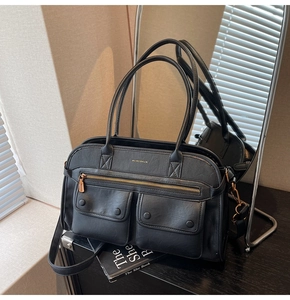 Detail view of large black multi-pocket handbag with gold zipper and dual handles