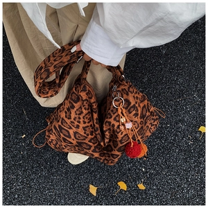 Detail of leopard print tote bag with colorful pompom charms and side drawstring design
