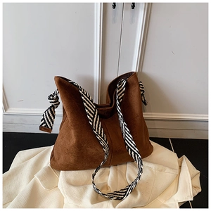 Detail of a brown matte suede tote bag with stylish black and white woven strap