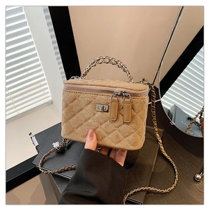 Close-up of khaki suede quilted vanity bag with metal turn-lock and gold-tone chain strap