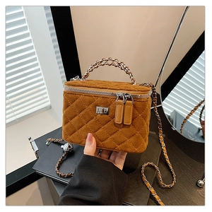 Close-up of brown quilted suede box bag with silver chain strap and metal lock
