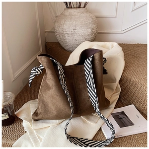 Brown suede tote bag detail with decorative side knot and woven wide shoulder strap