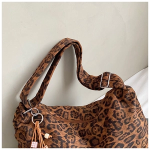 Detail of leopard print tote bag with metal zipper and decorative charm tassel