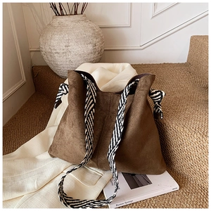 Close-up of brown matte suede tote bag featuring unique black and white woven rope strap