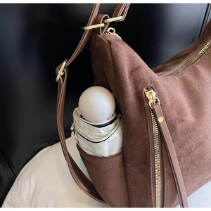 Detail view of large brown suede tote bag side pocket with a white folding umbrella
