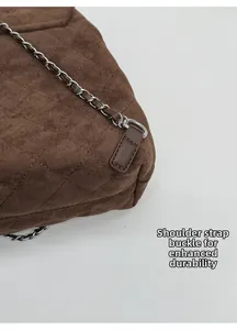 Détail de la boucle en D argentée et bandoulière sur sac à dos marron en daim