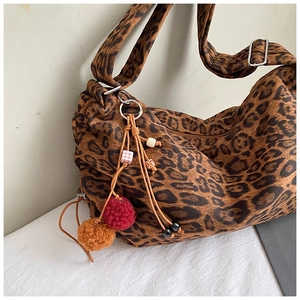 Detail of leopard print tote bag with colorful plush pom-pom and beaded charms