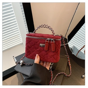 Detail of burgundy velvet quilted box bag with gold twist lock and chain strap