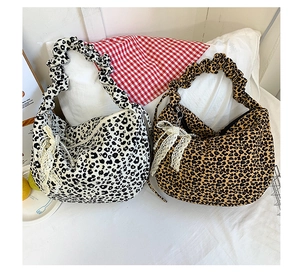 Detail view of leopard print shoulder bags with bow ties and pearl charms on a white bed