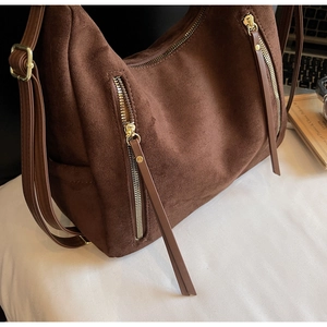 Detail of dark brown faux suede hobo bag with gold zippers and adjustable shoulder strap