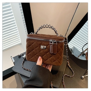 Close-up of dark brown quilted velvet crossbody bag with silver twist handle and chain