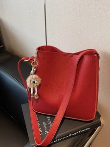 Sac seau chic en cuir grainé rouge avec un charmant pendentif en peluche pour un look mode