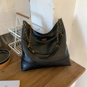 Detail einer schwarzen Stepptasche mit goldener Kette und edlem Drehverschluss aus Metall