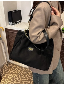 Large black pleated tote bag with leather strap and yellow brand patch for daily commute