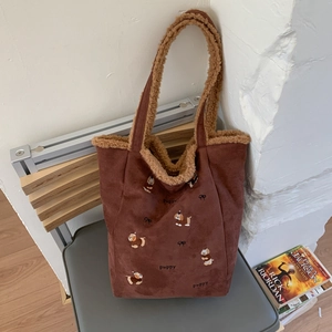 Close-up of corduroy bucket bag featuring cute puppy embroidery and faux shearling trim