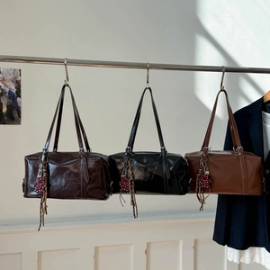 Detailed close-up of three glossy Boston bags with bear charms and fringe tassels