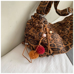 Detail of leopard print tote bag featuring plush pom-poms and vintage bead accents