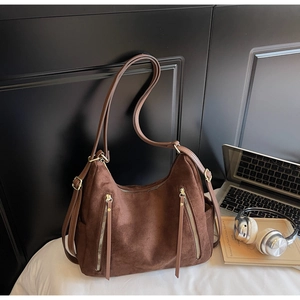 Detail of dark brown frosted suede tote bag with metal zippers and adjustable strap