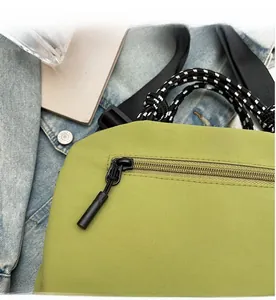 Detailed close-up showing the smooth black zipper and fabric texture of the green canvas bag