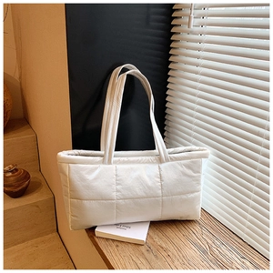 Detail of white quilted puffer tote bag with padded texture and slim shoulder straps
