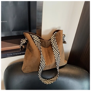 Close-up of brown suede tote bag with a striking black and white striped woven strap