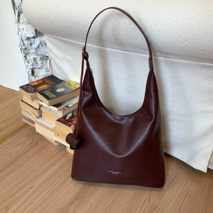 Dettaglio della borsa tote in pelle rosso vino scuro con testo del marchio su sfondo bianco