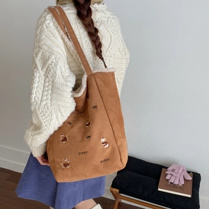 Detailed shot of brown corduroy tote with puppy embroidery and white faux fur trim