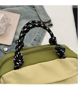 Detail of nylon tote bag featuring green-beige contrast and braided rope knot handles