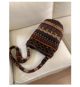 Detail of plush knitted tote bag with colorful geometric patterns on a beige sofa