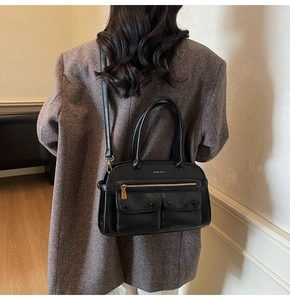 Detail of black faux leather tote with functional front pockets and metallic zippers