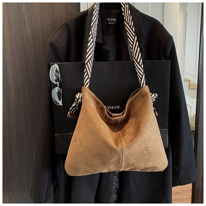 Detail of brown faux suede tote bag featuring contrast black and white striped shoulder strap